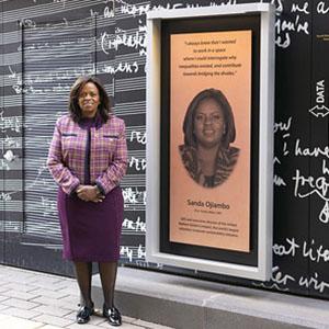 Sanda Ojiambo standing next to her plaque along Scholars Walk at the University of Minnesota