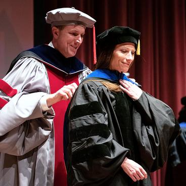 PhD candidate Kimberly Horner is hooded by Professor Ryan Allen at commencement 2024 ceremony
